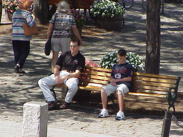 a father and son resting on a bench at Quincy Market in Boston Massachusetts